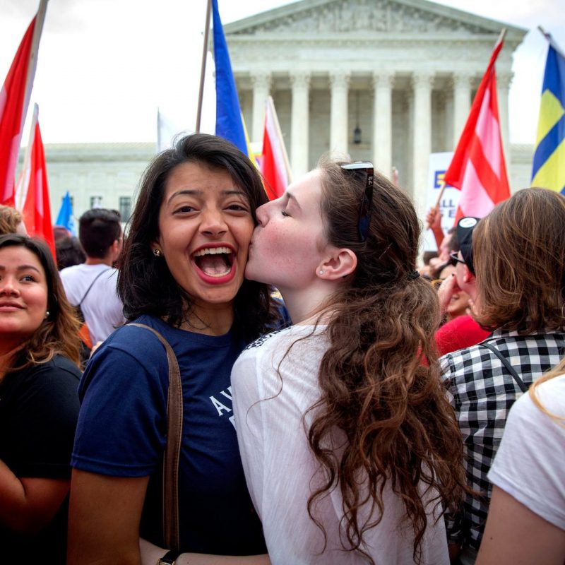 two women in crowd, one kissing the other on the cheek