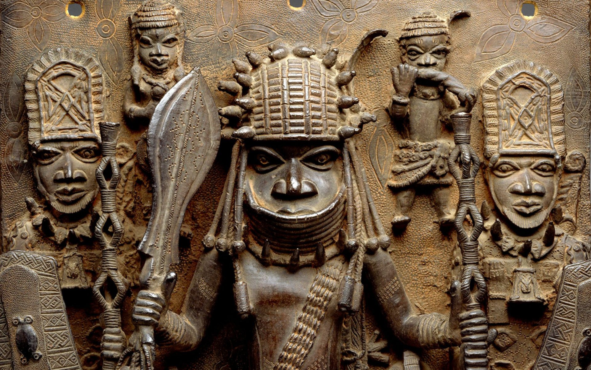 5 tribal men facing forward, depicted through bronze artwork 