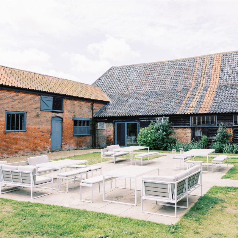 Converted barn wedding venue with outdoor lounge furniture in centre