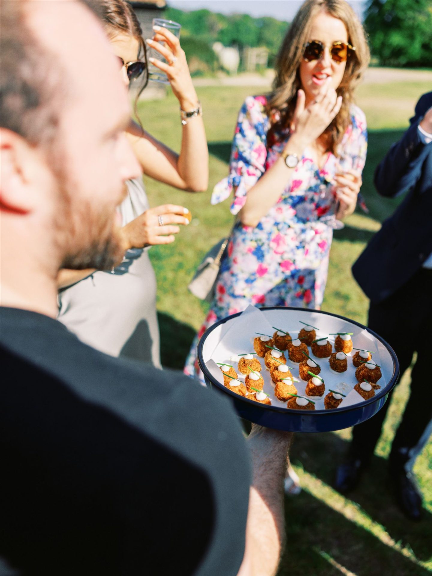 man holding arancini canapes with his back to the camera, guest looking excitedly at the tray