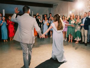 Bride and groom hand in hand whilst dancing